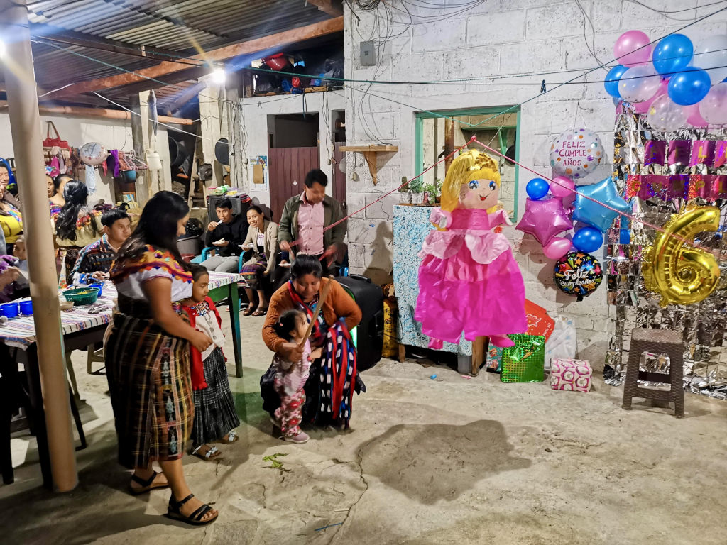 A mayan family celebrating the birthday of their daughter by hitting a pinata in San Juan La LAguna