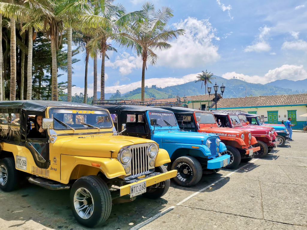 A lineup of colorful jeeps parked at a town square in colombia that are the best way how to get to the cocora valley hike