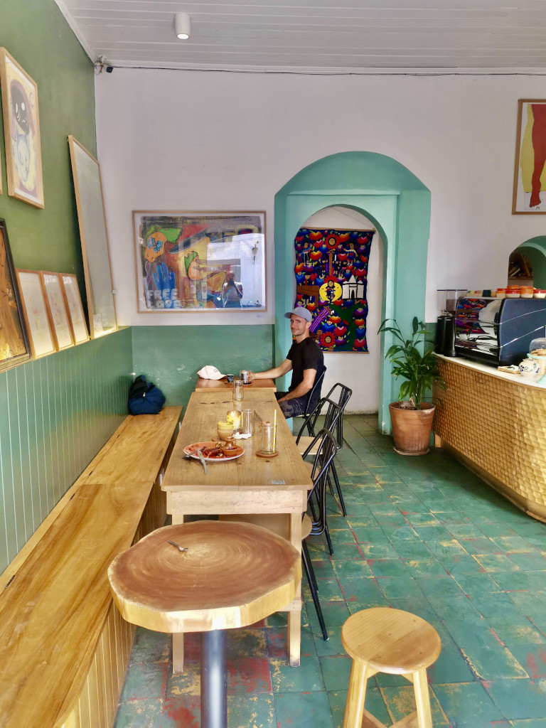 A man sitting at a long table in a colorful cafe