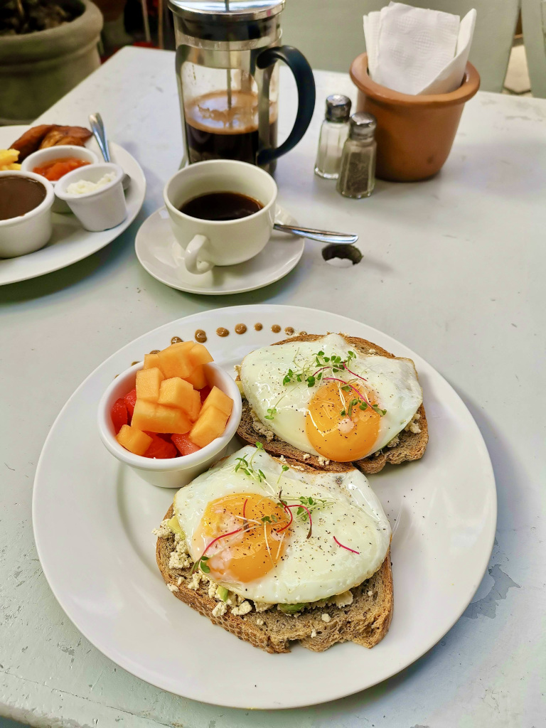 A plate with fried eggs on toast and a French press full of coffee behind it at one of the best cafes Antigua Guatemala has to offer