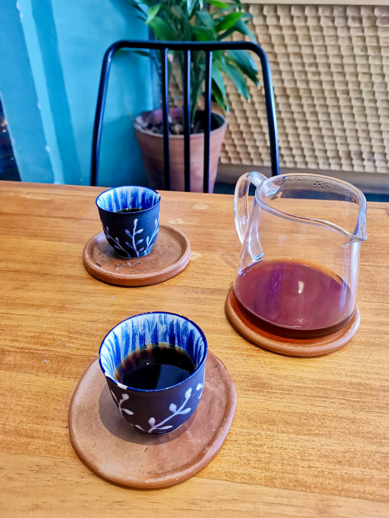 Two coffee cups and a glass coffee can on a wooden table