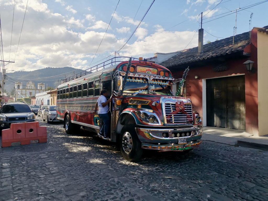 A colorful Chicken bus driving down a cobblestone street one of the best ways how to get from Guatemala City to Lake Atitlan