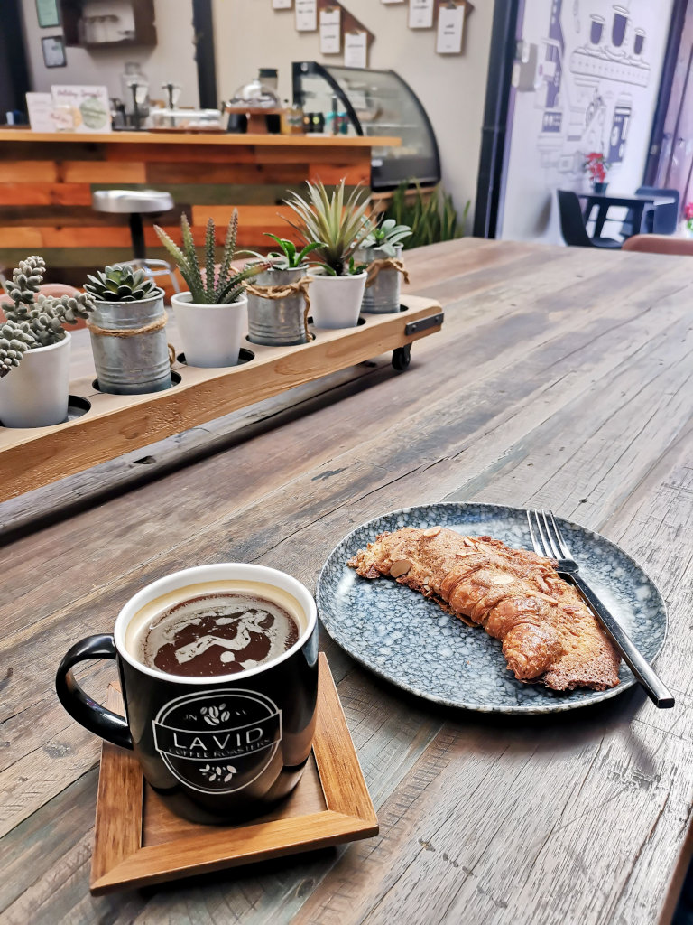 A cup of coffee and a croissant sitting on a table at one of the best cafes Antigua Guatemala has to offer