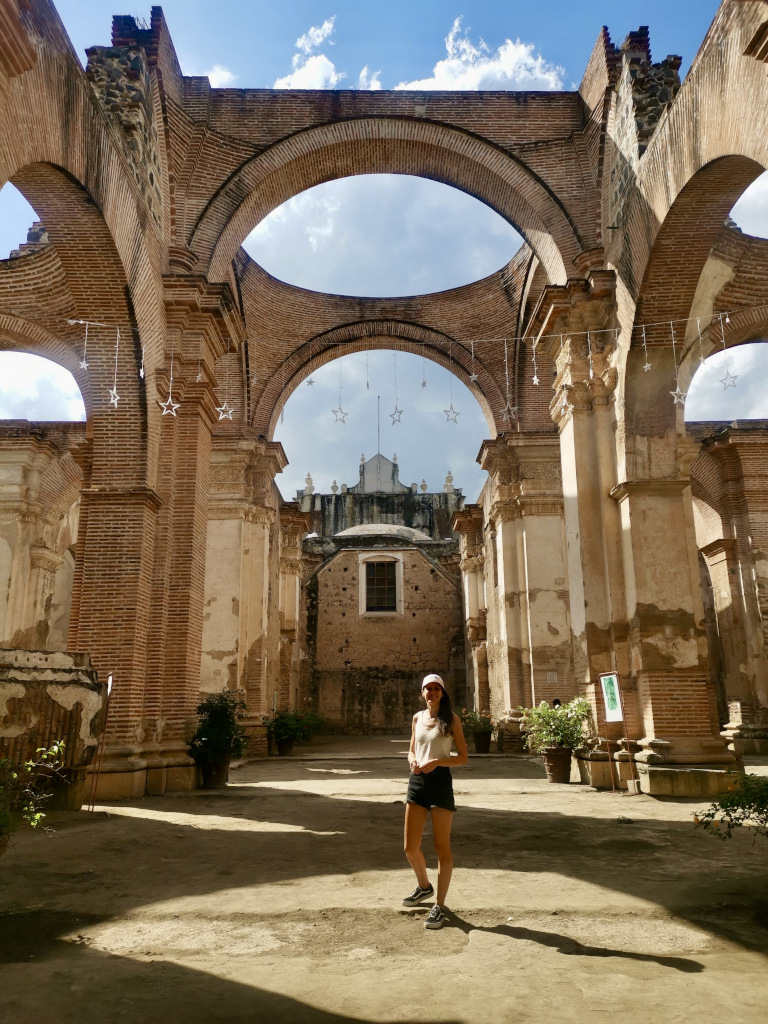 A woman standing in the middle of some ruins in Antigua Guatemala