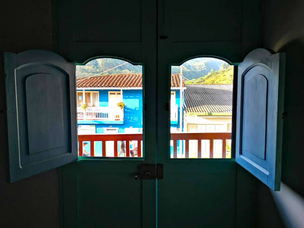 View on a colorful house out of a blue wooden window