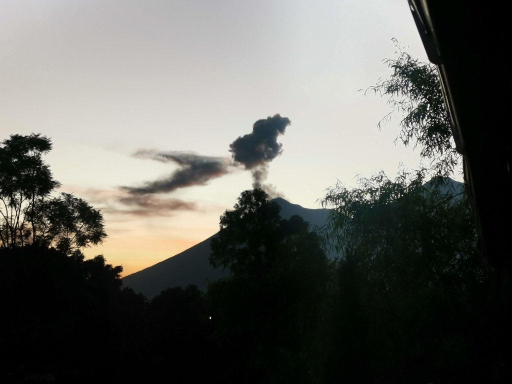 Fuego erupting with a smoke cloud in the sky at sunset 