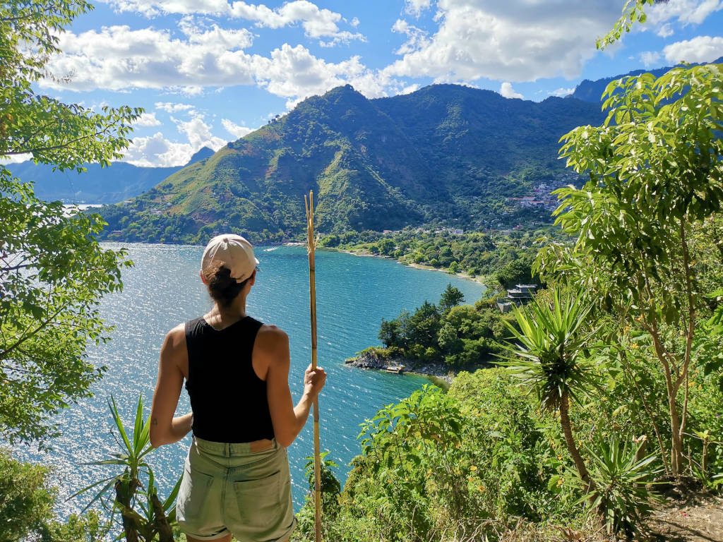 A woman holding a stick while on a hike on Lake Atitlan in Guatemala