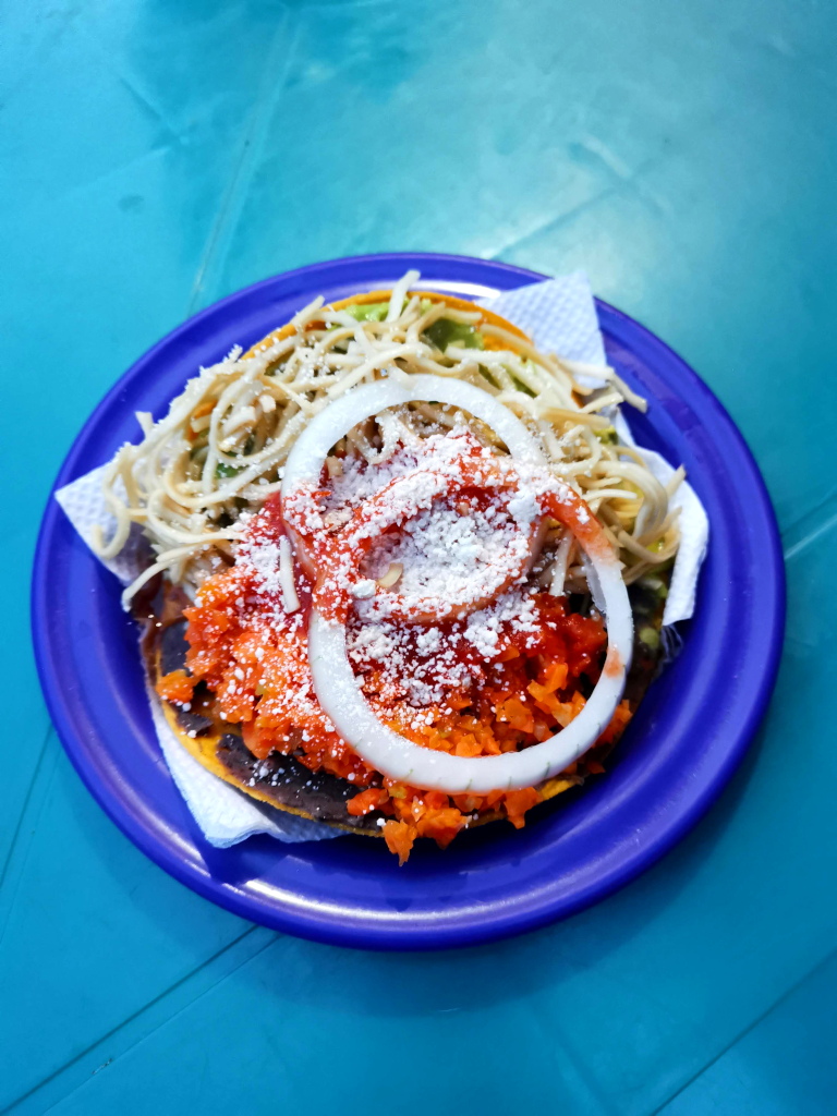 A plate with a tostada covered in toppings