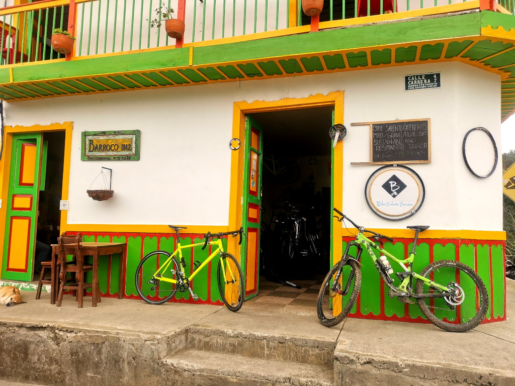 Dirty mountainbikes leaning outside an open door of a colorful building in Salento