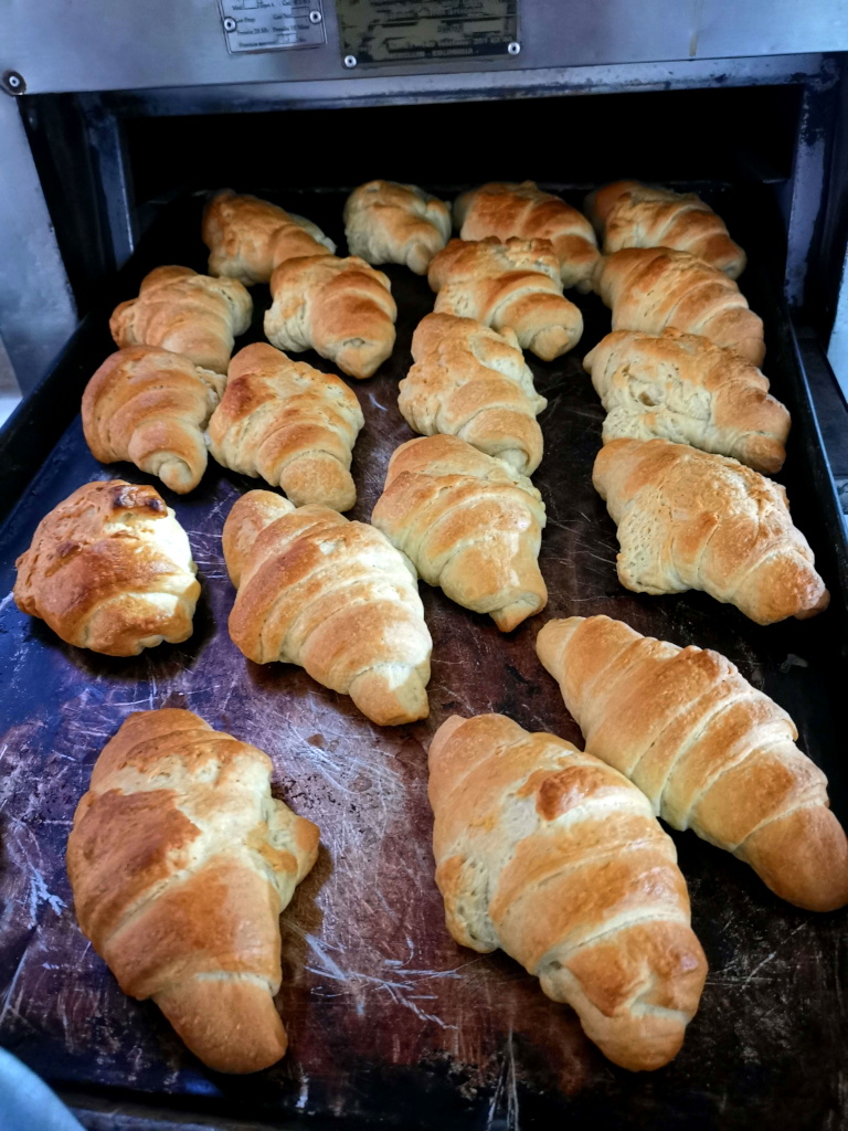 Freshly baked croissants on an oven tray