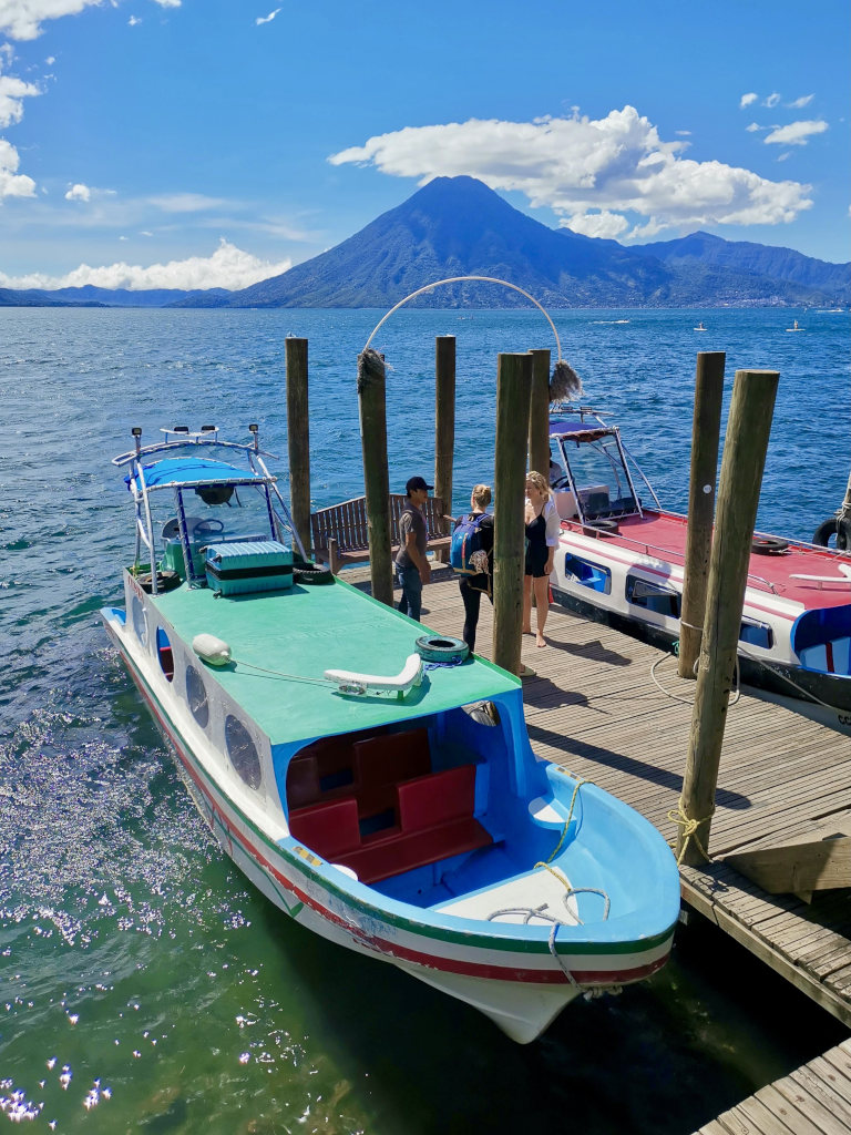 A group of tourists standing on a dock next to a water taxi waiting for a ride on Lake Atitlan Guatemala