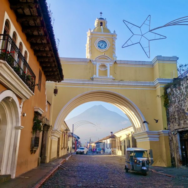 A tuktuk driving though the yellow Catalina Arch - one of the must-things to see in Antigua Guatemala