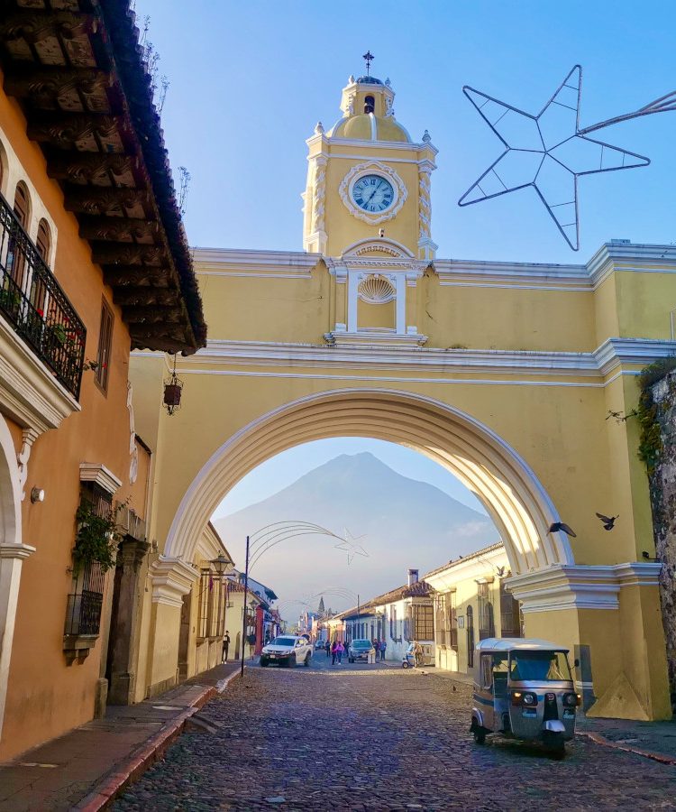 A tuktuk driving though the yellow Catalina Arch - one of the must-things to see in Antigua Guatemala