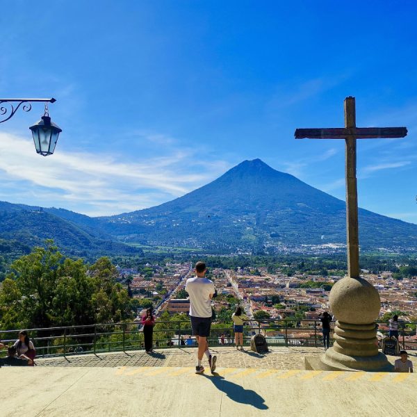 A man standing on top of Cerro de la Cruz overlooking Antigua Guatemala with volcanoes in the back