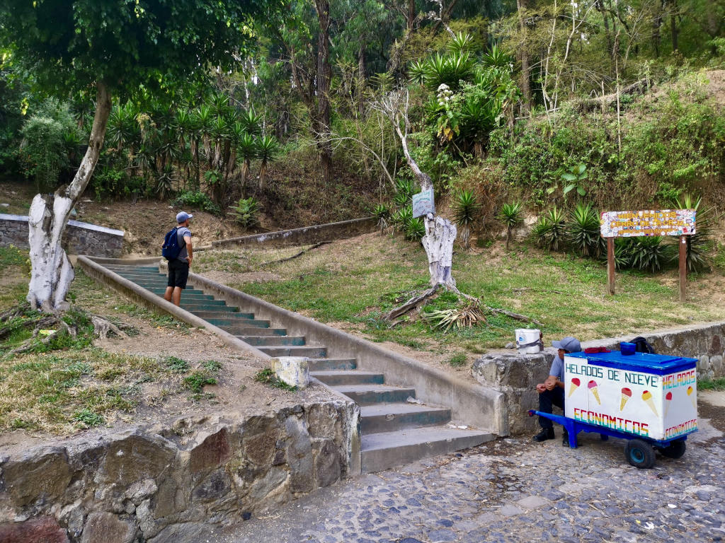A man standing on some stair next to a man selling ice cream at the base of the Cerro de la Cruz hike
