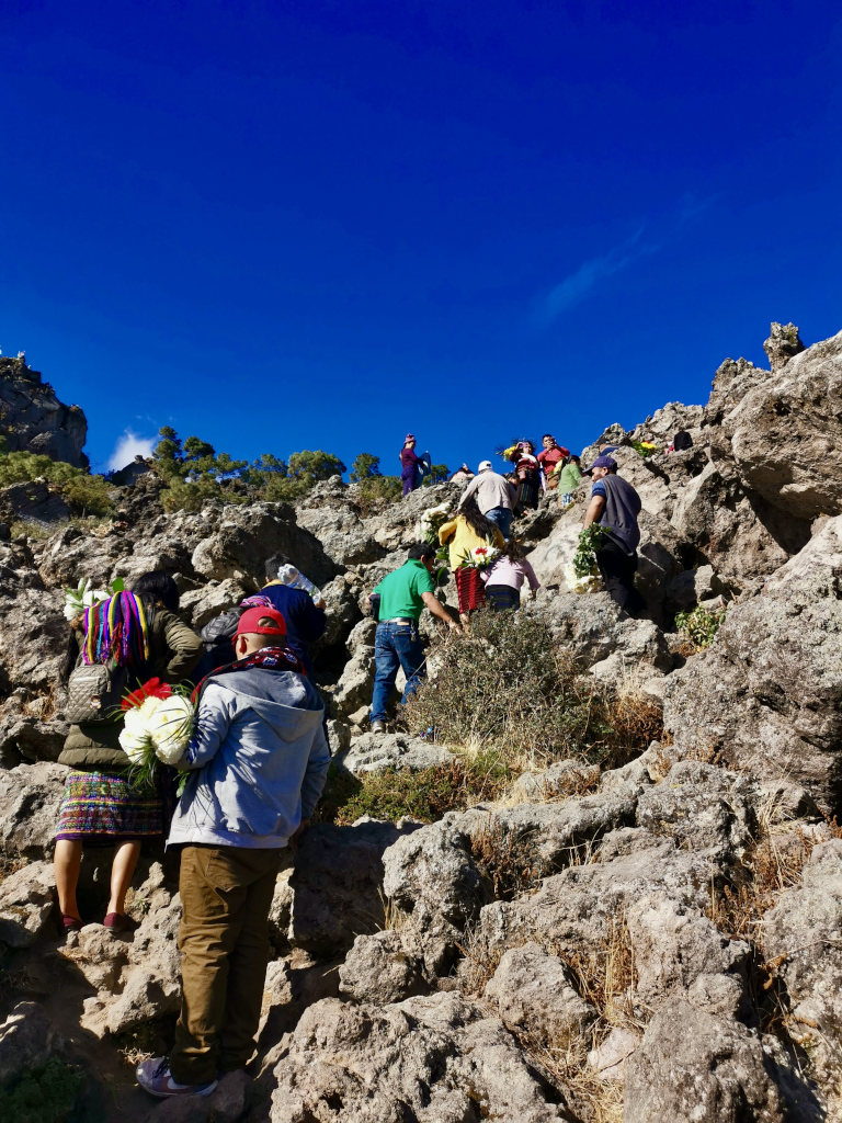 A group of Guatemalan people climbing to the top of a rocky hill top