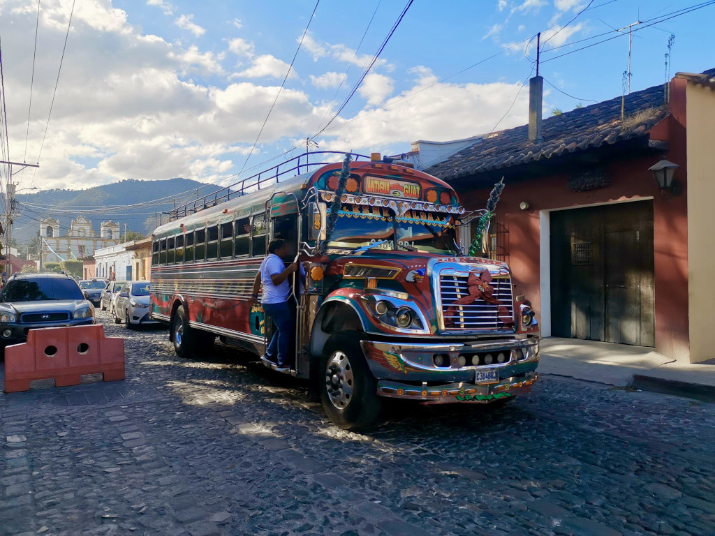 A chicken bus driving down the road in Antigua Guatemala with Christmas decorations on the front