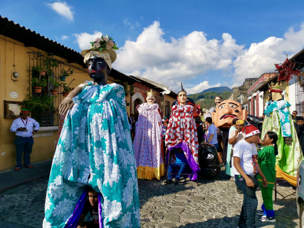 A parade of people in colorful costumes walking down a cobblestone street for Christmas in Antigua Guatemala