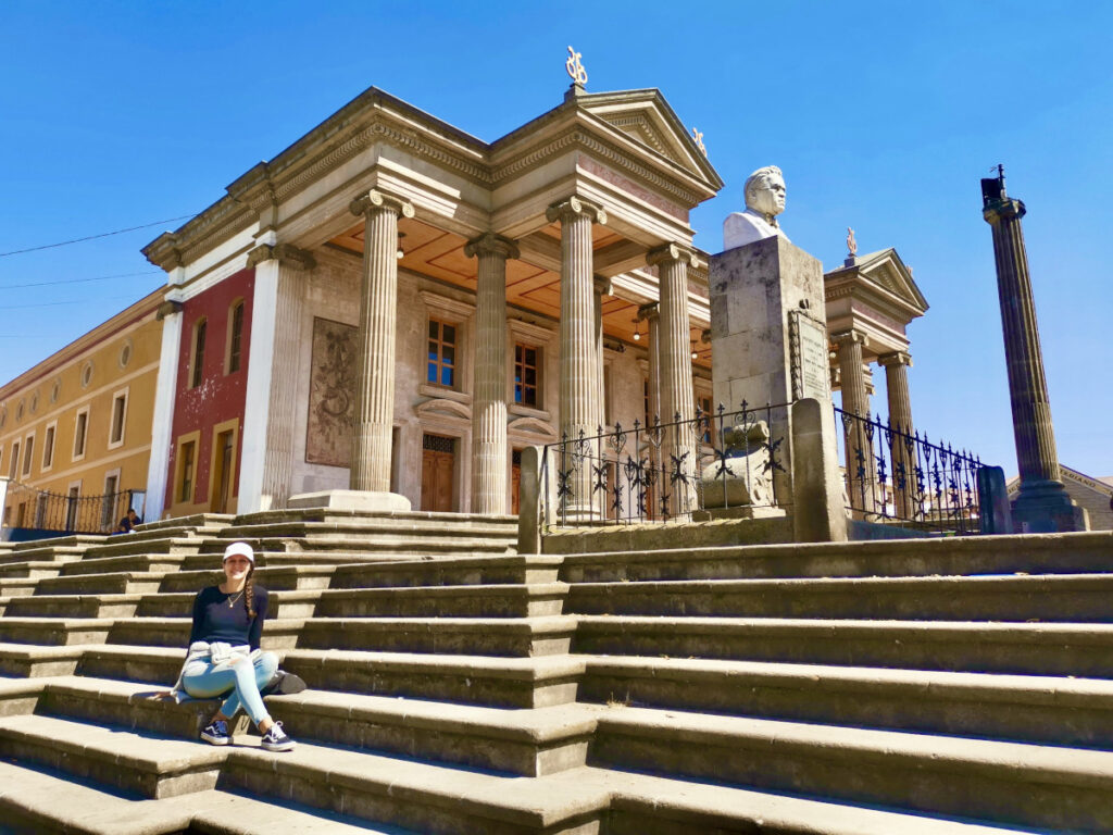 A woman sitting on the stairs in front of the theater in Quetzaltenango (Xela)