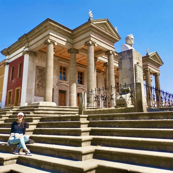 A woman sitting on the stairs in front of the theater in Quetzaltenango (Xela)