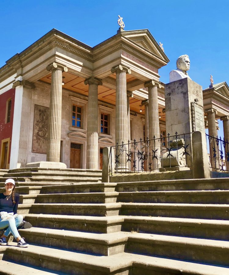 A woman sitting on the stairs in front of the theater in Quetzaltenango (Xela)