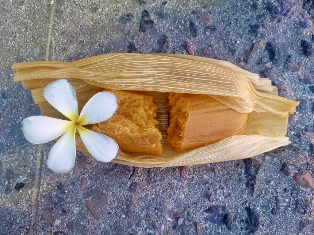 An open tamale with a flower next to it
