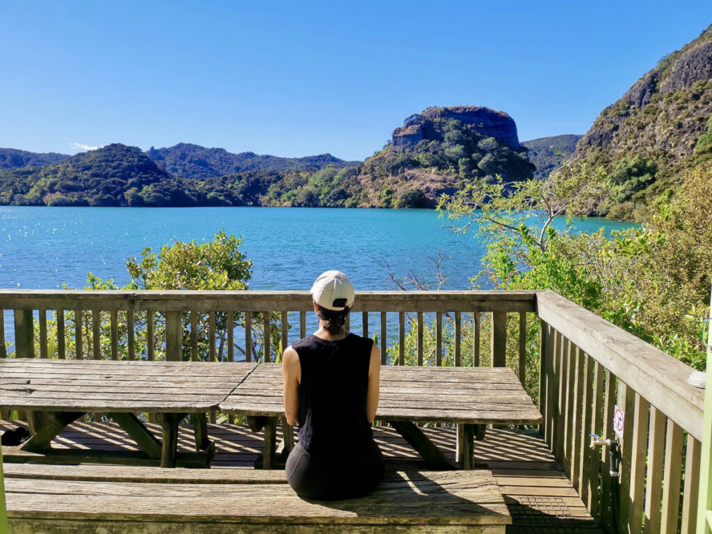 A women sitting on the terrace of Lane Cove Hut overlooking the crystal clear water
