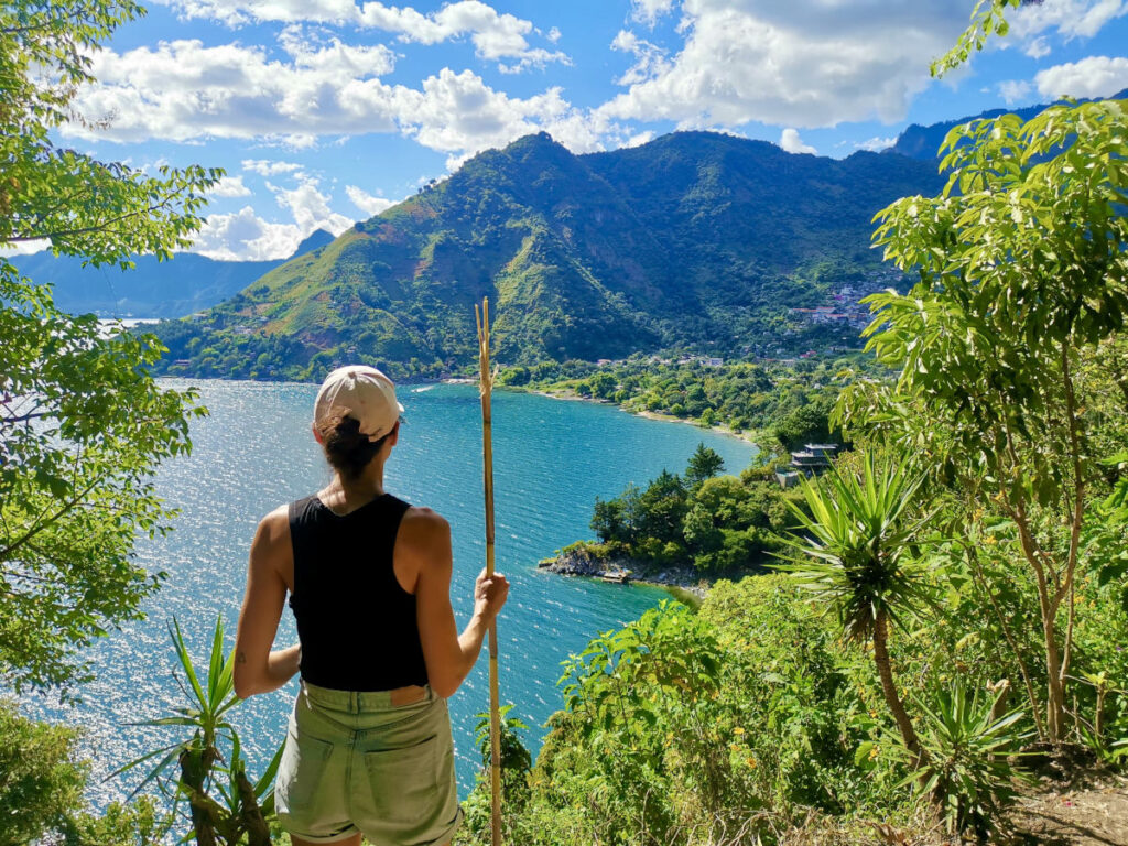 A woman with a hiking stick overlooking Lake Atitlan on the Lower Mayan Trail