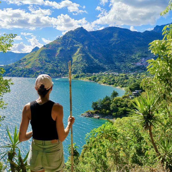 A woman with a hiking stick overlooking Lake Atitlan on the Lower Mayan Trail