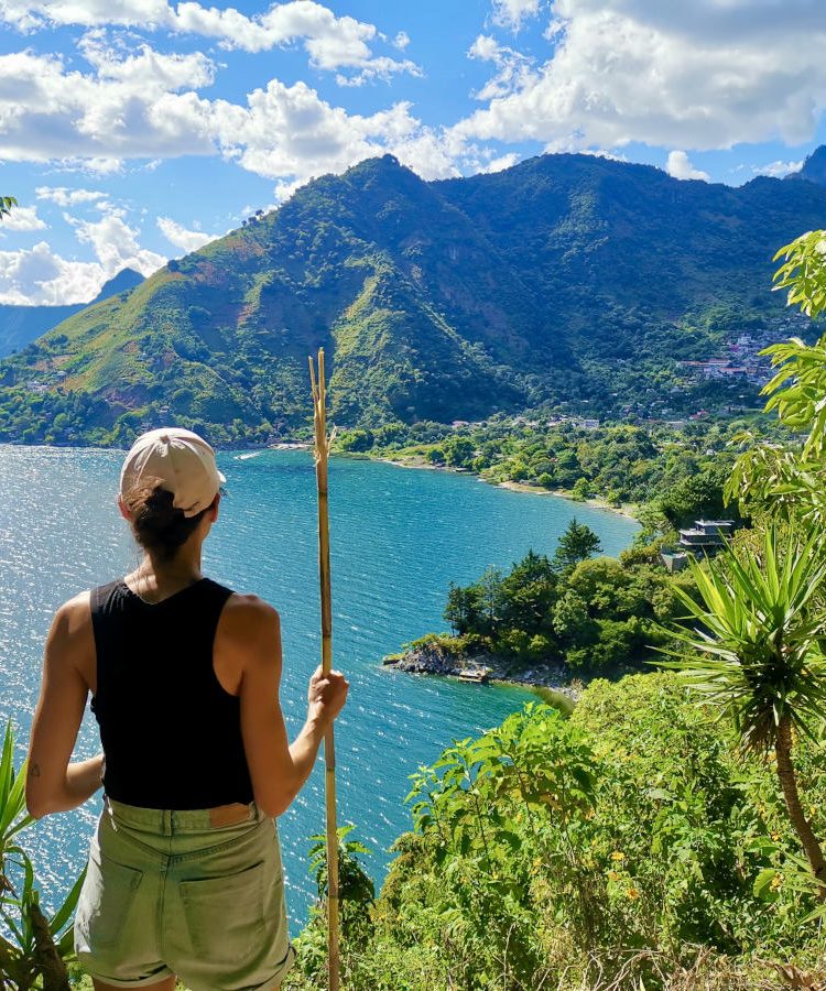 A woman with a hiking stick overlooking Lake Atitlan on the Lower Mayan Trail