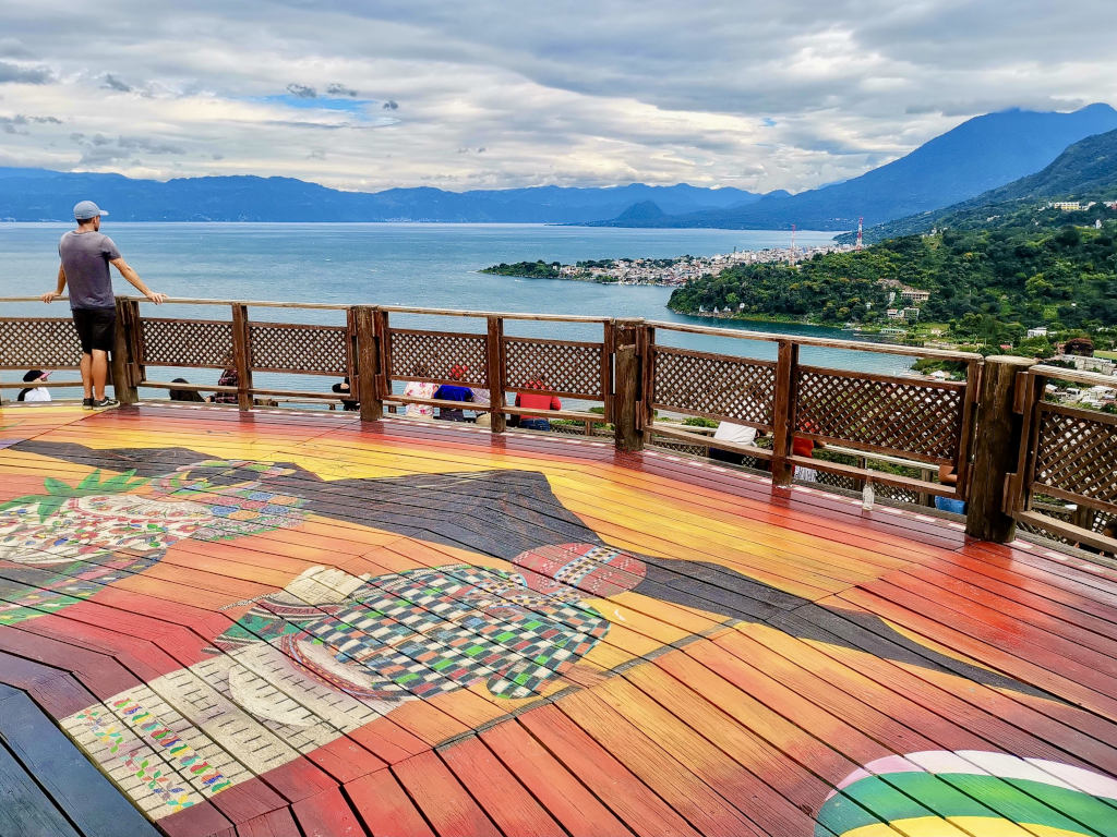 A man standing on top of a colorful wooden lookout at the San Juan La Laguna Mirador on Lake Atitlan Guatemala