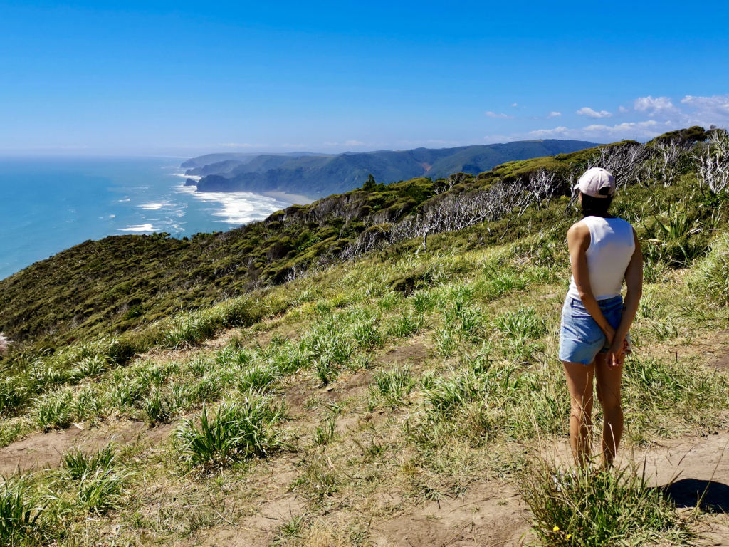 A woman in a white singlet and denim shorts admiring the view of the coast at the start of the Mercer Bay Loop Walk