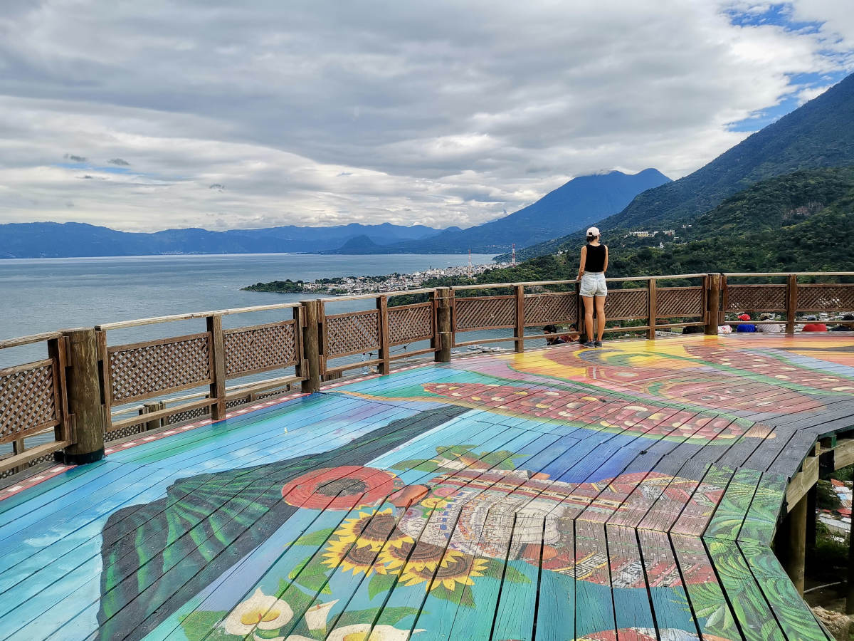 A woman standing on top of the San Juan La Laguna Mirador which is a colorful wooden lookout with spectacular views of Lake Atitlan, Guatemala and nearby volcanoes