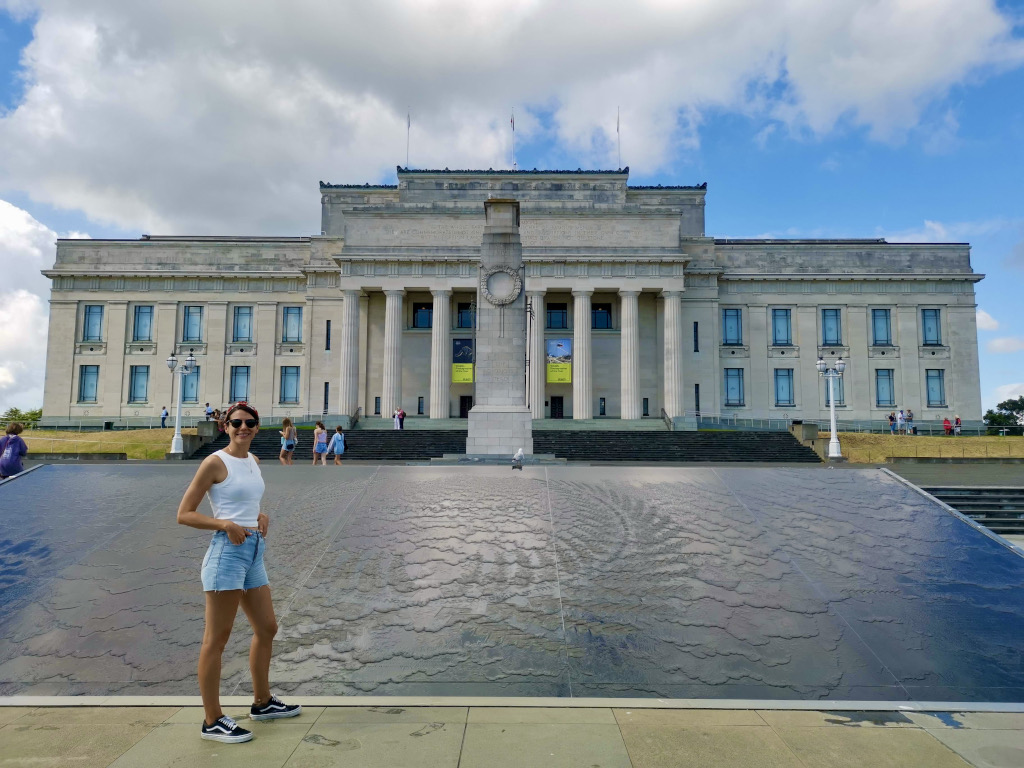 A woman standing in front of the Auckland museum in the Auckland Domain