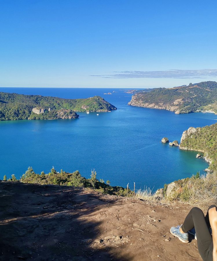 A women sitting on top of Dukes Nose Hike overlooking the blue harbor