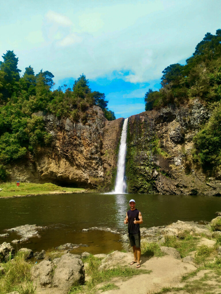 A man in a black singlet standing in front of the Hunua Falls