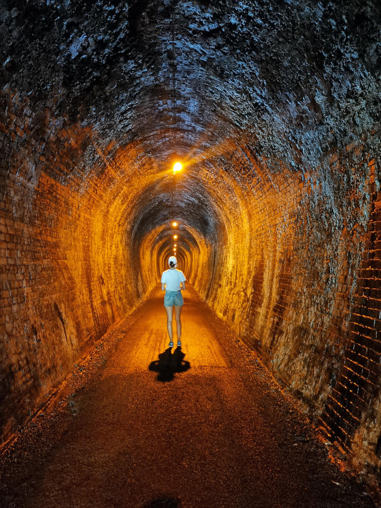 A woman walking down the Karangahake Gorge tunnel