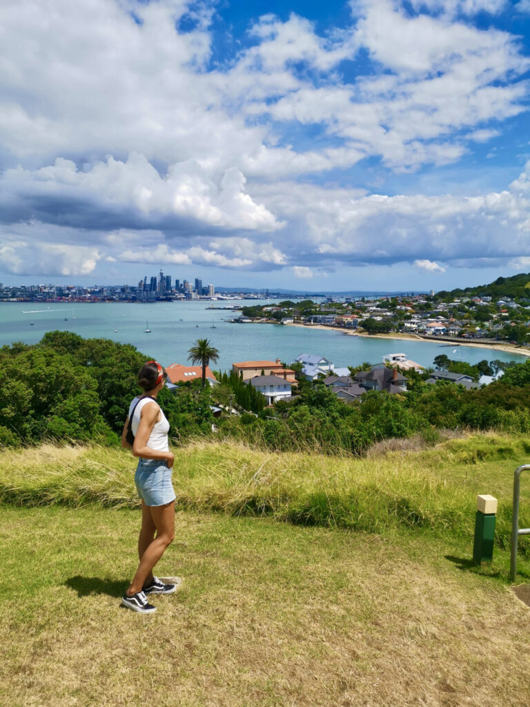 A woman in a white singlet looking at the view from Northead which is one of the best walks in Auckland