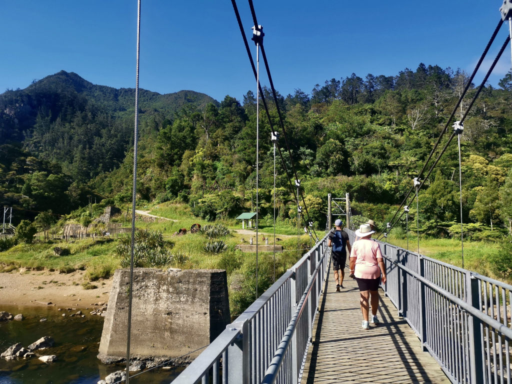 Two people walking over a bridge in the Karangahake Gorge