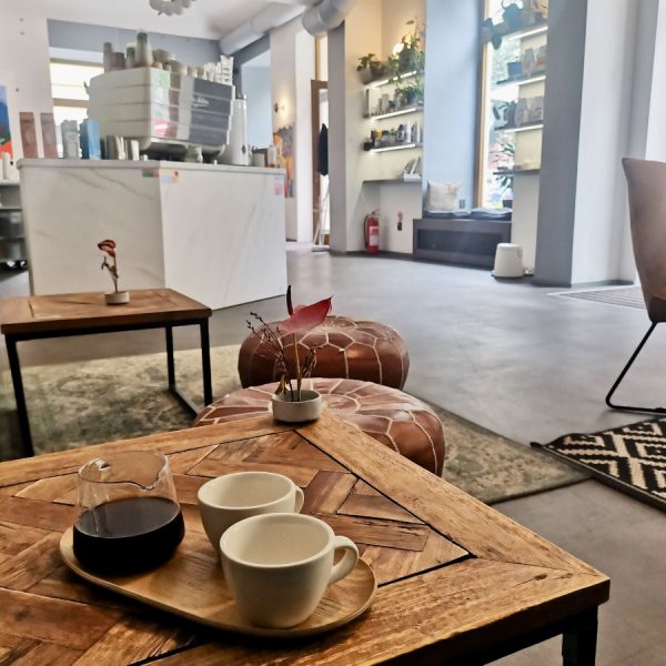 A set of two empty coffee cups and a jar with black coffee sitting on a wooden table in one of Prague's best specialty cafes