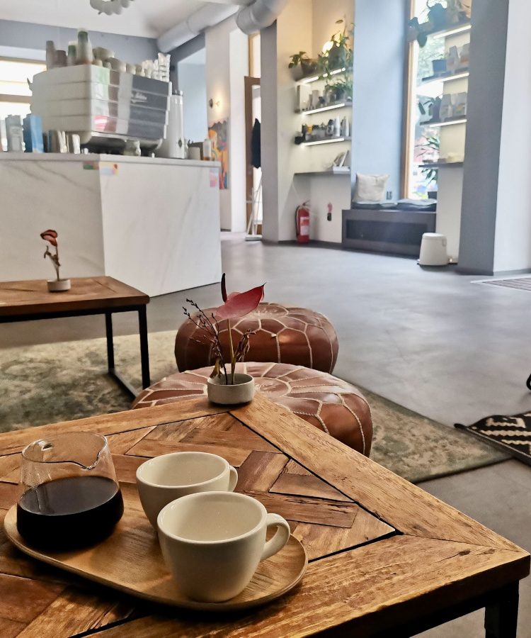 A set of two empty coffee cups and a jar with black coffee sitting on a wooden table in one of Prague's best specialty cafes