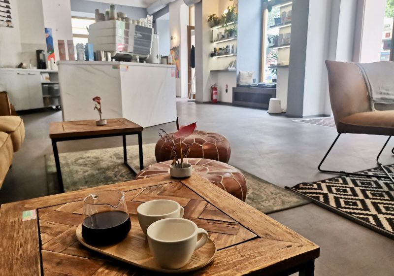 A set of two empty coffee cups and a jar with black coffee sitting on a wooden table in one of Prague's best specialty cafes