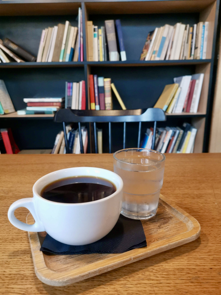 A cup of coffee sitting on a table next to a glas of water