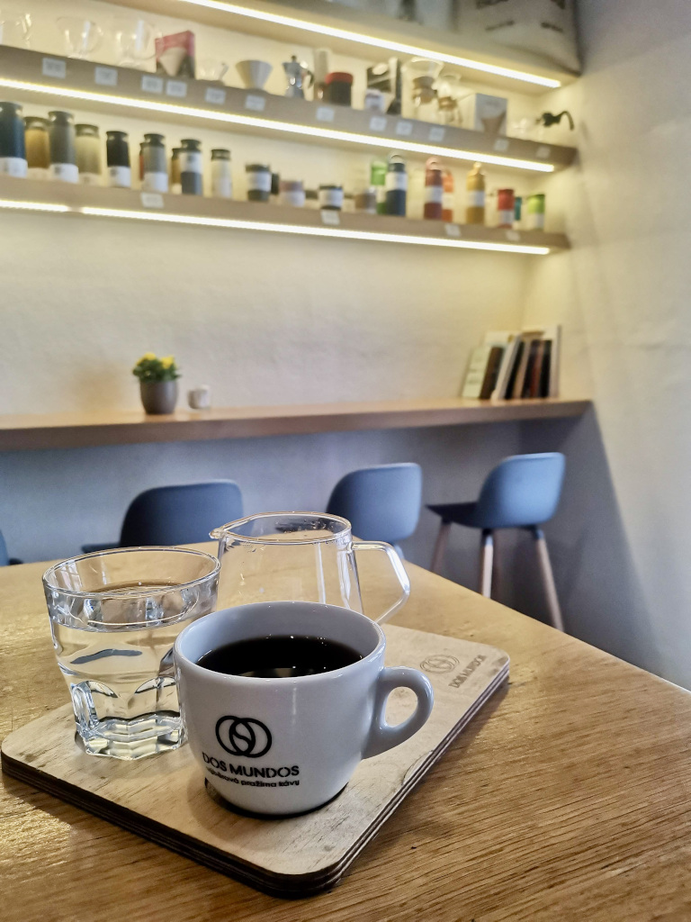 A cup of coffee sitting on a table at Dos Mundos Cafe in Prague