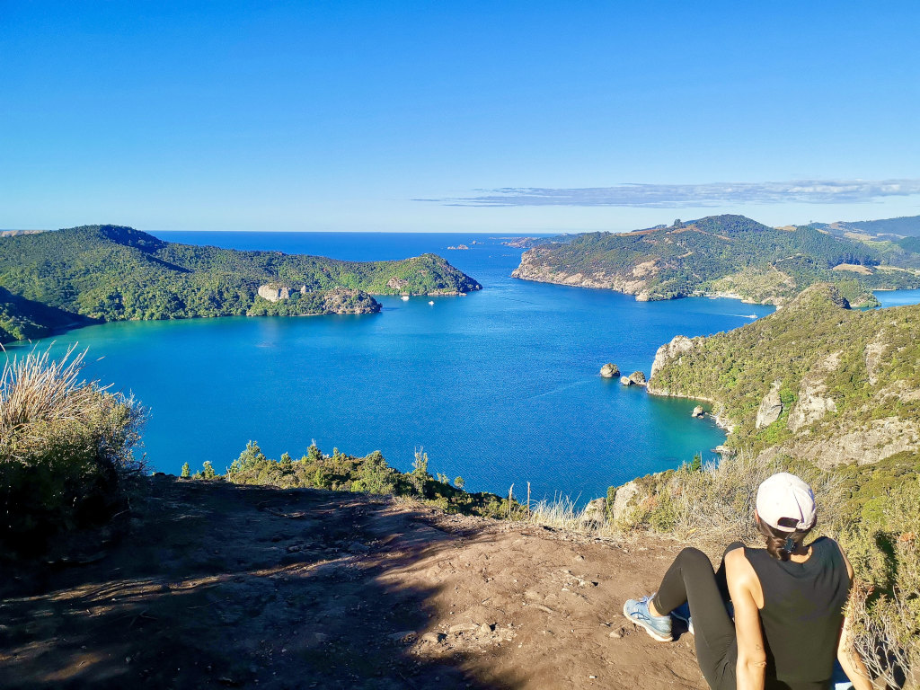 A woman sitting at the top of the dukes nose hike as part of a northland road trip