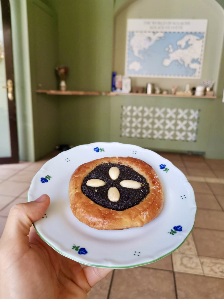 A hand holding a plate with a Kolache on it which is a traditional Czech pastry