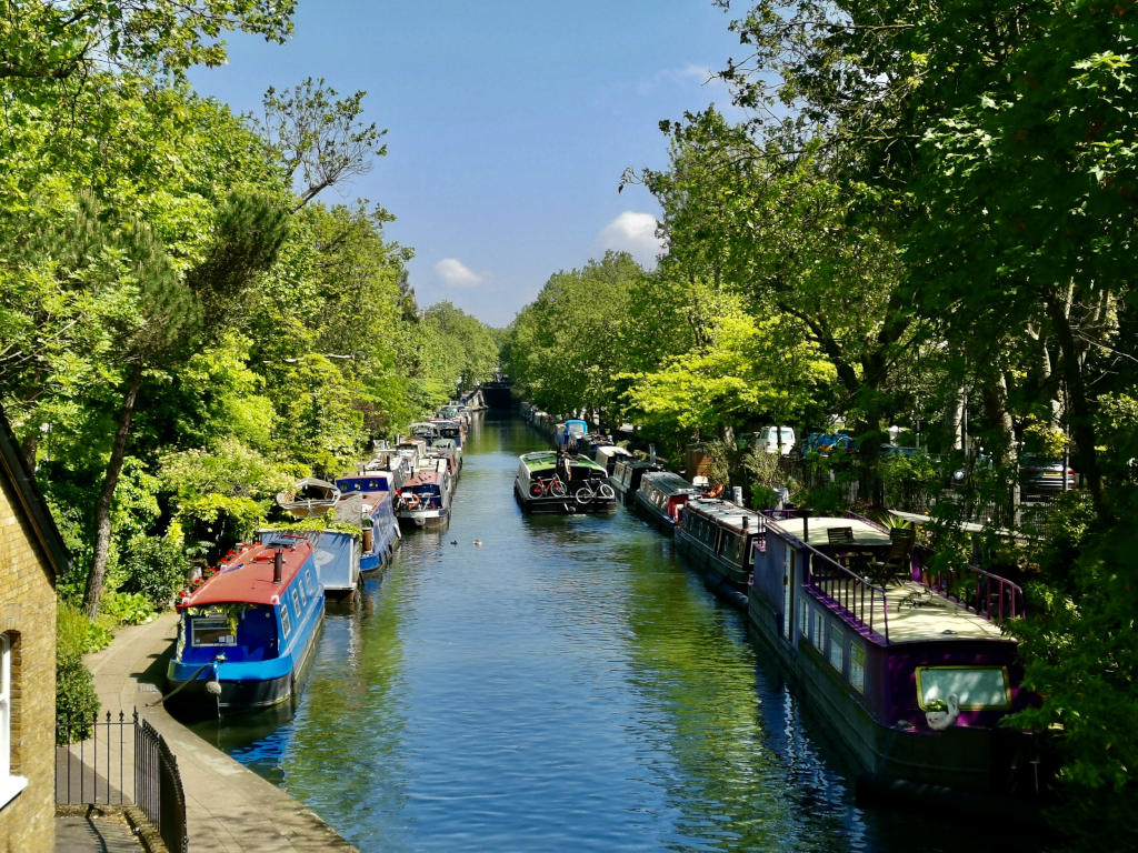 A canal in little venice London with house boats lined along the sides of the canal