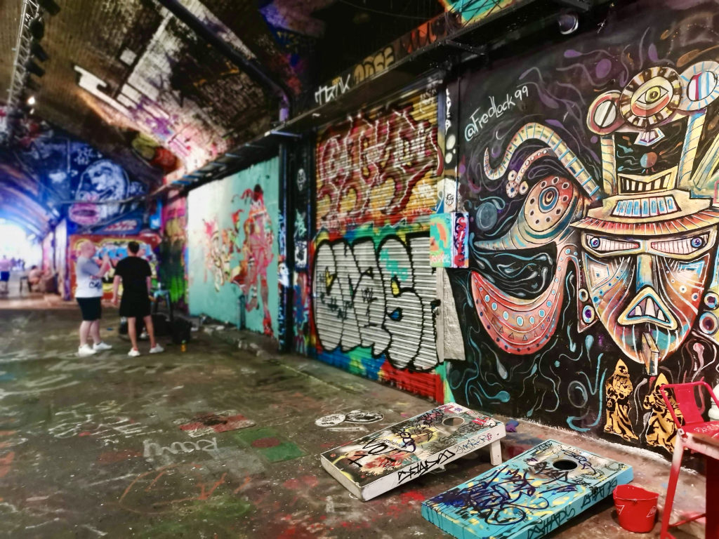 Artist working on a new piece of art inside a tunnel covered in street art within the graffiti tunnel in london