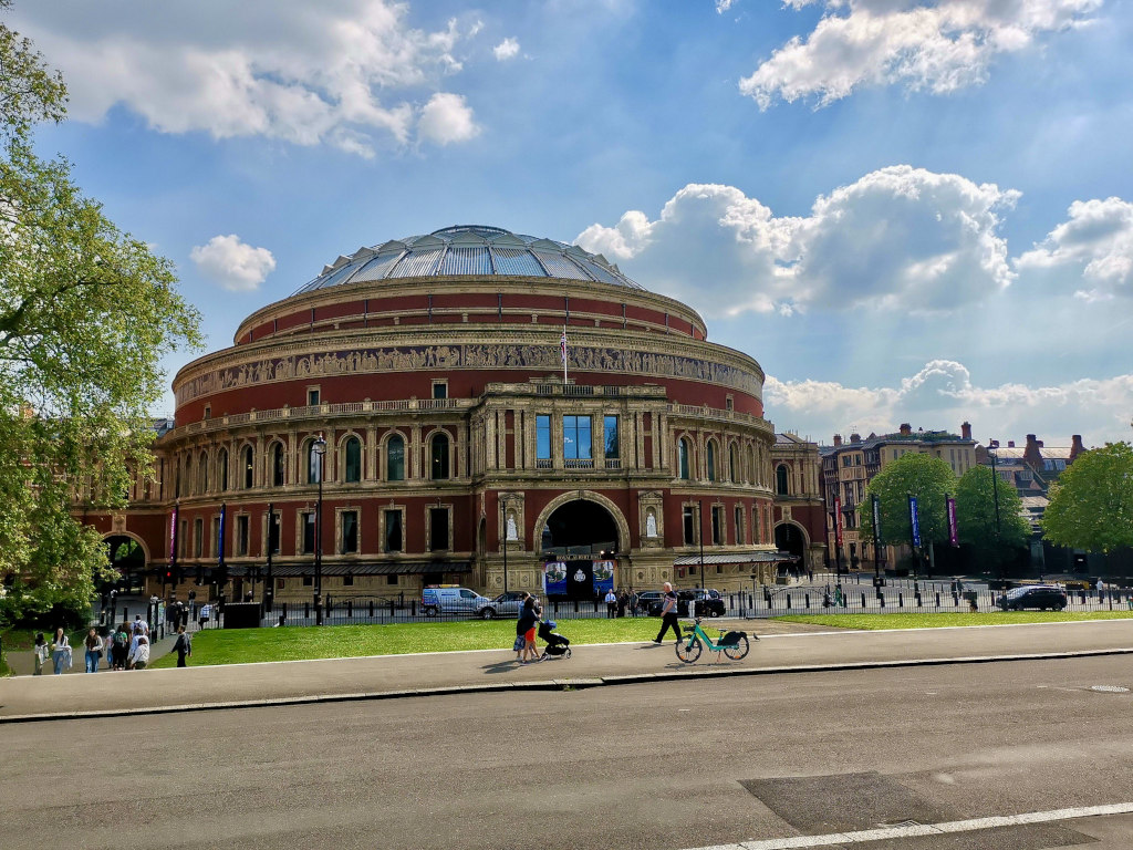 People walking outside in the sun in front of Royal Albert Hall in London England