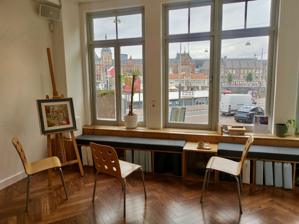 The seating area of a cafe with views of amsterdam train station